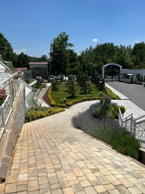 Мощёная дорожка через парк курорта с подстриженным газоном и лавандой
